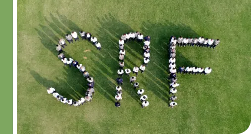 Aerial view of SRF’s employees standing in a field in the shape of their brand name
